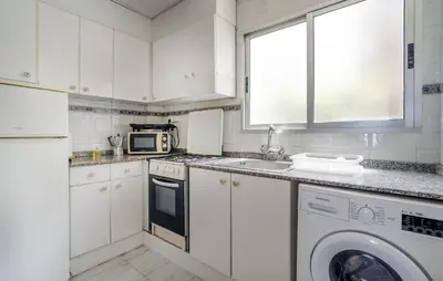 a white kitchen with a sink and a washing machine at Lovely Apartment In Faro De Cullera in Faro de Cullera