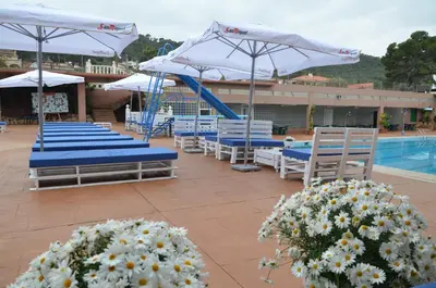a group of chairs and umbrellas next to a pool at Complejo Turistico la Pinada in Gilet