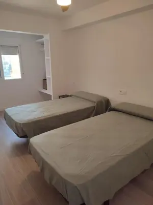 two beds in a hotel room with a window at Apartamento en Primera Línea in Cullera