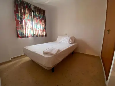 a small bed in a room with a window at Perla III Solo Familias Serviplaya in Casas Las Basas