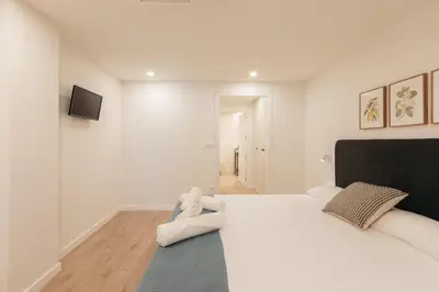 a white bedroom with a large bed and a television at Doce de Colón C in Requena