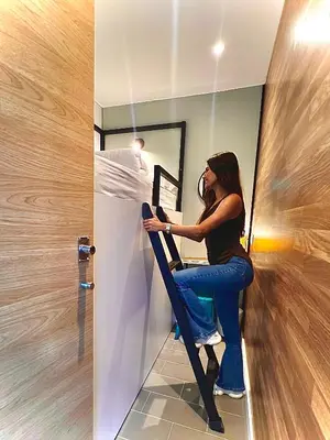 a woman sitting on a ladder in front of a mirror at U-nit Hostel Central Park in Valencia