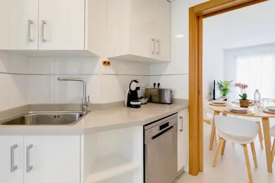 a kitchen with white cabinets and a sink and a table at Valencia Beach Home 8 in Valencia