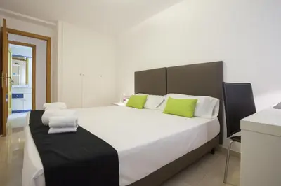 a bedroom with a large white bed with green pillows at Apartments Serrería II in Valencia