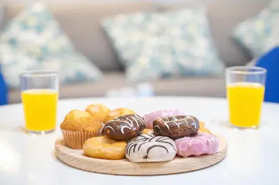 a plate of donuts on a table with two glasses of orange juice at Dúplex tranquilo frente al mar en Xilxes Terraza, parking y WiFi in Chilches