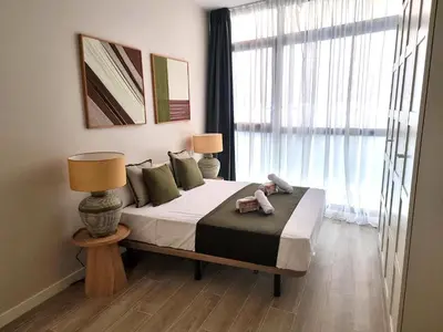 a bedroom with a bed with two lamps and a window at MD Senda del Aire in Valencia