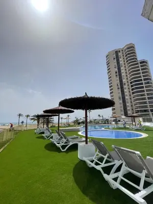 a row of chairs and umbrellas next to a pool at Sobre el mar in Cullera