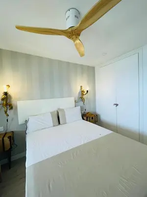 a bedroom with a white bed with a ceiling fan at Sobre el mar in Cullera