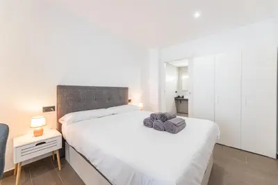 a bedroom with a white bed with two towels on it at Suite Deluxe Valencia - Beach II Apartments in Valencia