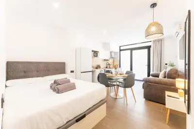 a bedroom with a bed and a kitchen with a table at Suite Deluxe Valencia - Beach II Apartments in Valencia
