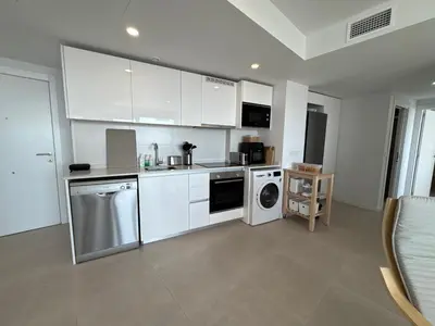 a kitchen with white cabinets and a washer and dryer at Gran Canet Salva, moderno apartamento con terraza y vistas al mar in Canet de Berenguer