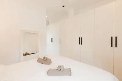 a white bedroom with white cabinets and two towels at Spacious villa with private pool & garden for 4 in Partida de La Cañada