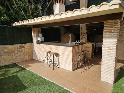 an outdoor kitchen with stools in a brick building at Amazing Villa with swimming pool in Torrent