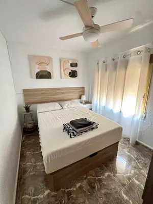 a bedroom with a bed with a ceiling fan at Apartamento edificio JUMAR in Cullera