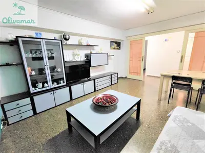 a living room with a coffee table and a kitchen at Apartamento céntrico y cerca del mar en Tavernes in Tavernes de Valldigna