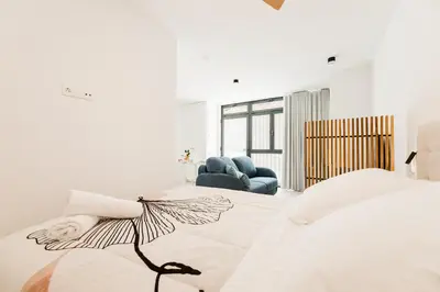 a white bedroom with a bed and two chairs at Fantástico loft en Valencia in Valencia