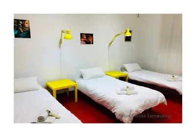 three beds in a room with yellow tables at B&B Una Habitación Propia in Valencia