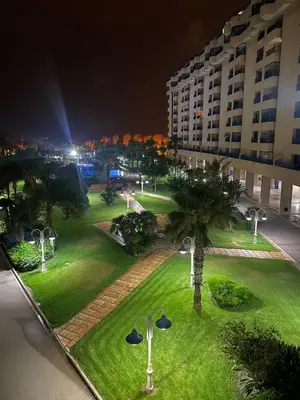a park with palm trees and a building at night at Patacona beach apartment in Valencia