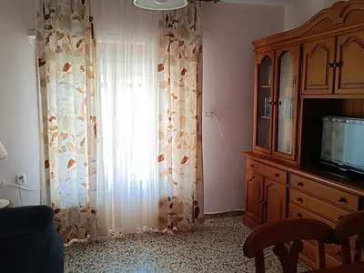 a living room with a tv and a window at Cozy Beachside Apartment in Tavernes de Valldigna