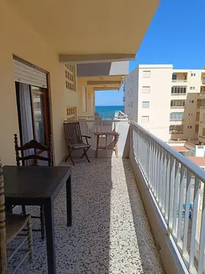 a balcony with chairs and a table and the ocean at Cozy Beachside Apartment in Tavernes de Valldigna