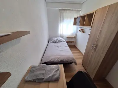 a small room with a bed and a wooden table at Piso Burjassot - Valencia in Burjasot