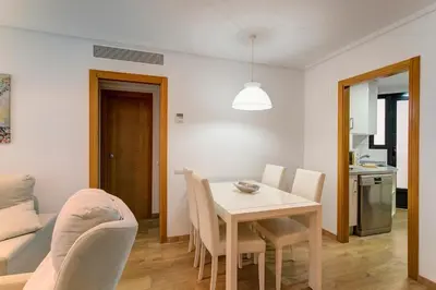 a dining room and living room with a table and chairs at Beach apartment in Valencia