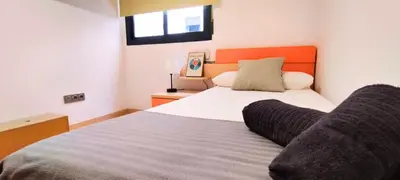 a bedroom with a large bed with an orange headboard at Apartamento cerca Playa in Puerto de Sagunto