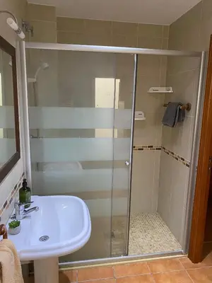 a shower with a glass door next to a sink at Pensión Dani in Casinos