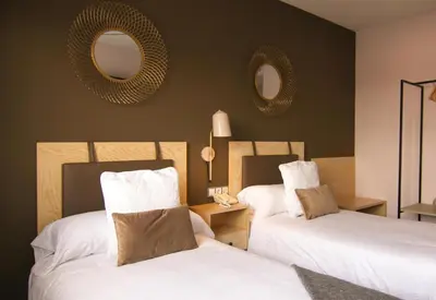 two beds in a room with mirrors on the wall at El Puig in El Puig