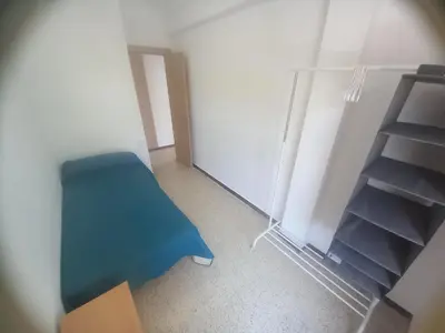 an empty room with a blue chair and a shelf at Estirpe, 4-7 in Cullera