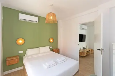 a bedroom with a white bed and a green wall at GuestReady - Lovely family home in El Cabanyal in Valencia