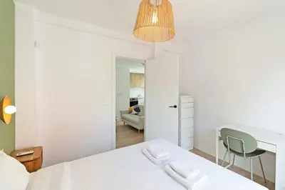 a white bedroom with a bed and a desk and a chair at GuestReady - Lovely family home in El Cabanyal in Valencia