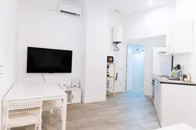 a white kitchen with a table and a tv on the wall at GuestReady - Bright home in Valencia in Valencia