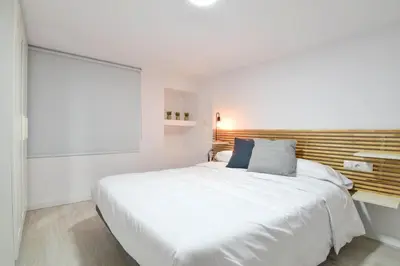 a bedroom with a large white bed with a wooden headboard at Puerto de Valencia 2 in Valencia