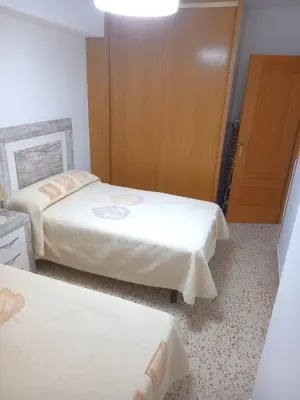 a bedroom with two beds and a wooden door at Sol, 3-20 in Cullera