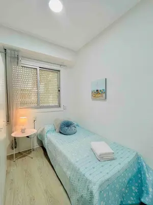 a bedroom with a bed and a table and a window at Cerca de Playa arenas con balcon in Valencia