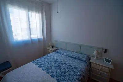 a bedroom with a blue bed and a window at Piso Playa de Canet in Canet de Berenguer