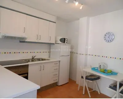 a kitchen with white cabinets and a white refrigerator at Piso Playa de Canet in Canet de Berenguer