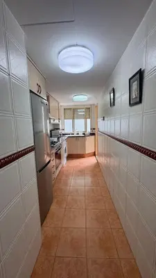 a hallway of a kitchen with a refrigerator and a counter at Apartamento entero Playa Perello Valencia in El Perelló