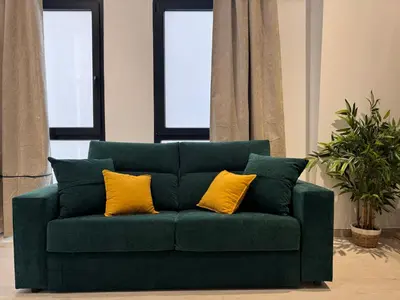 a green couch with two yellow pillows on it at Apartamento El Rincón de Darío in Valencia