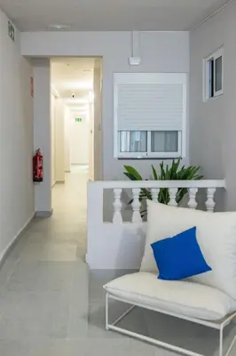 a living room with a white couch and a blue pillow at Carmen Beach Hostel Cullera in Cullera