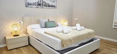 a white bedroom with a large bed with white sheets at Vacansis Valencia Bajo Torrefiel in Valencia