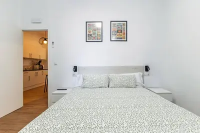 a white bedroom with a large bed and a kitchen at Quiet & Modern Apartment in Valencia