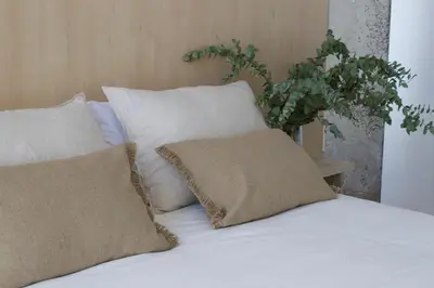 a bed with white sheets and pillows and a plant at BNO studio 1c in Aldaia