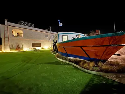 a boat sitting on the grass in front of a building at Barco - casa con jardín privado frente al mar in Mareny Barraquetas