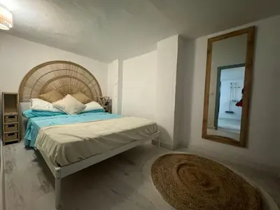 a bedroom with a bed with a mirror and a rug at Casa Playa El Perelló in El Perelló
