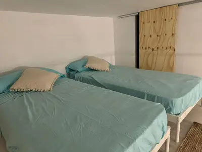 two beds in a room with green sheets at Casa Playa El Perelló in El Perelló