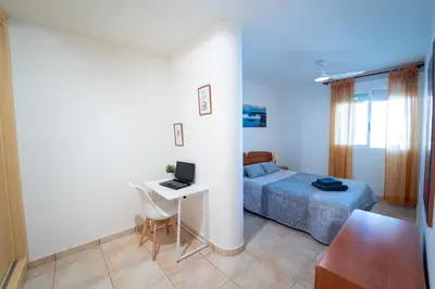 a bedroom with a bed and a desk with a laptop at Tu rincón frente al mar en Moncofa Ideal para dos in Moncófar
