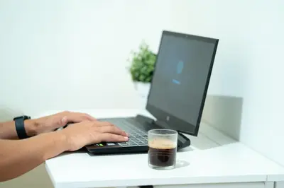 a person typing on a laptop with a cup of coffee at Tu rincón frente al mar en Moncofa Ideal para dos in Moncófar