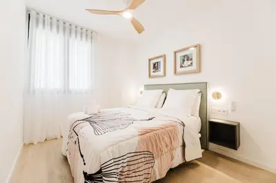 a white bedroom with a bed and a ceiling fan at Fantastico Apartamento en Valencia in Valencia